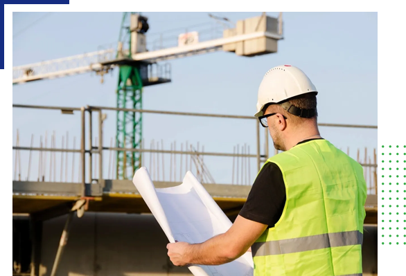 A man in safety vest and hard hat looking at plans.