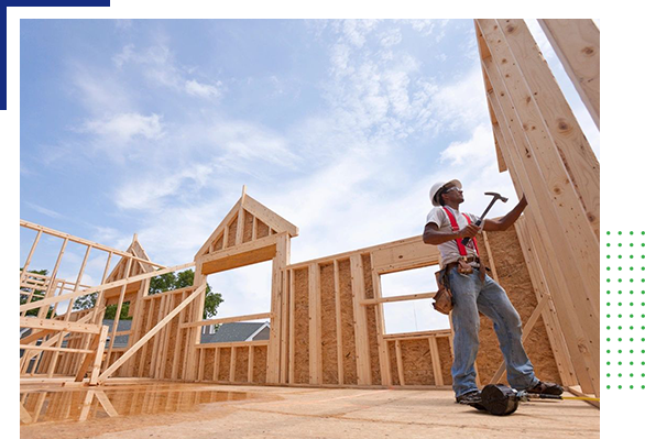 A man holding a hammer in front of a wooden structure.