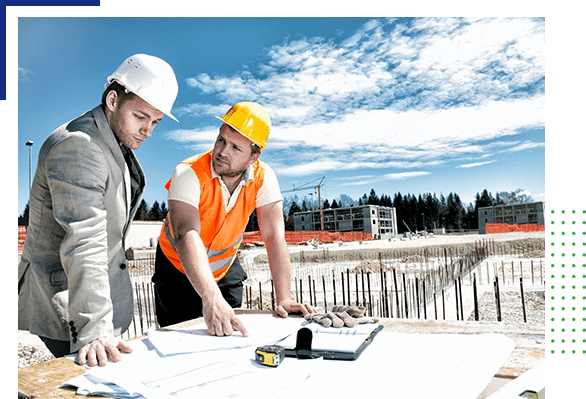 Two men in hard hats looking at plans on a construction site.